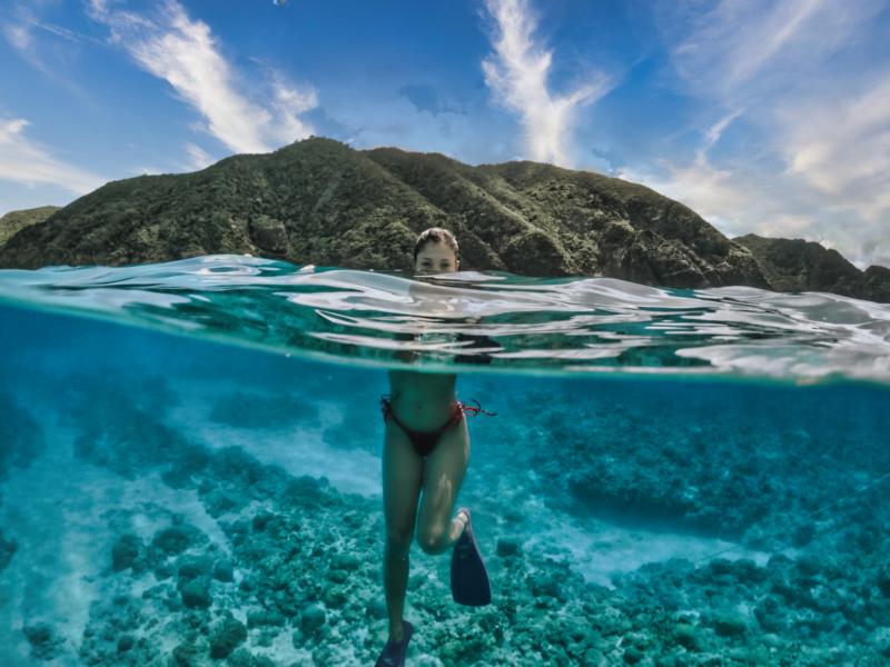 swimming in the shallow blue waters filled with coral reefs in Kerama islands, Okinawa