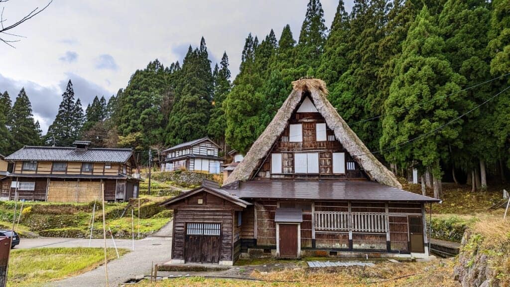 A thatched roof house in Gokayama with evergreen trees in the background