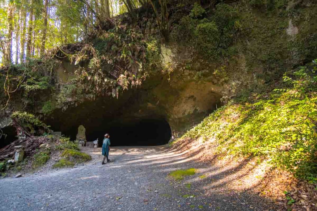 Woman walking up two large cave opening in kagoshima, Japan