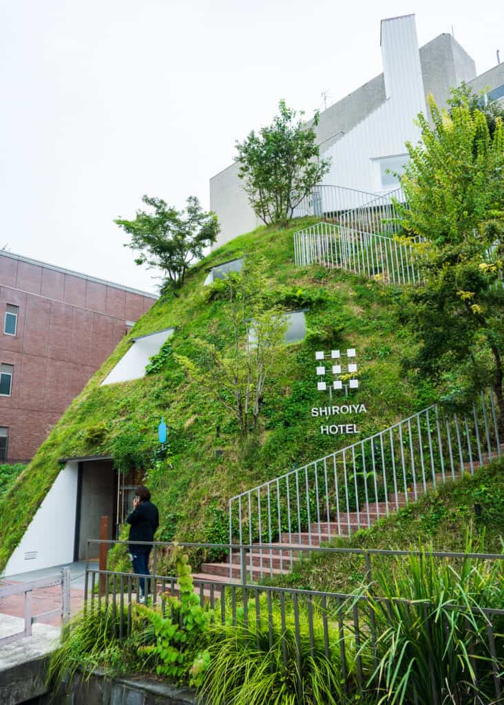 shiroiya hotel exterior with cement wall covered with greenery and moss in japan