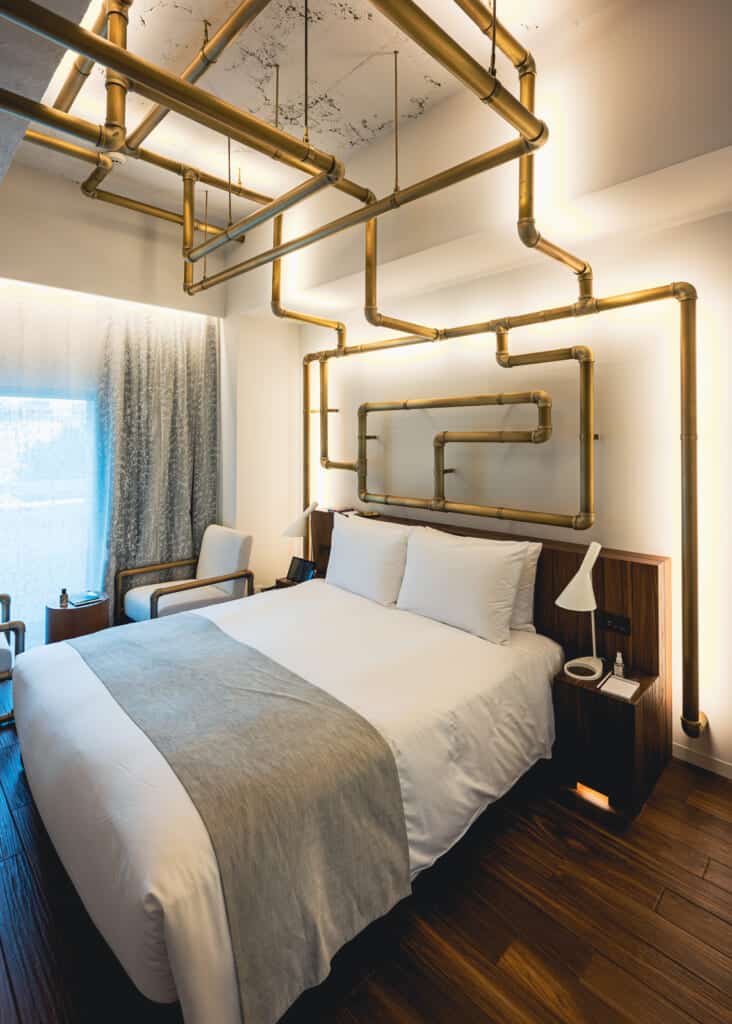 bedroom with bed and a network of brass pipes interwoven above the bed in japan