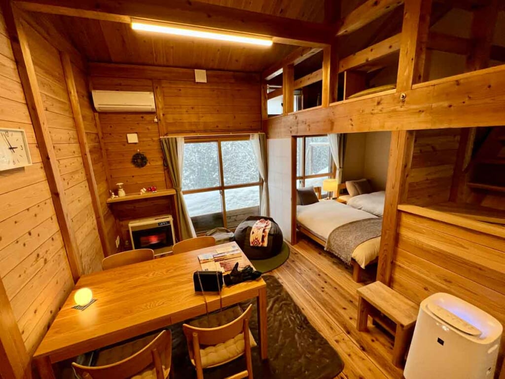 interior space of Japanese cottage with beds, a table, and snow outside window