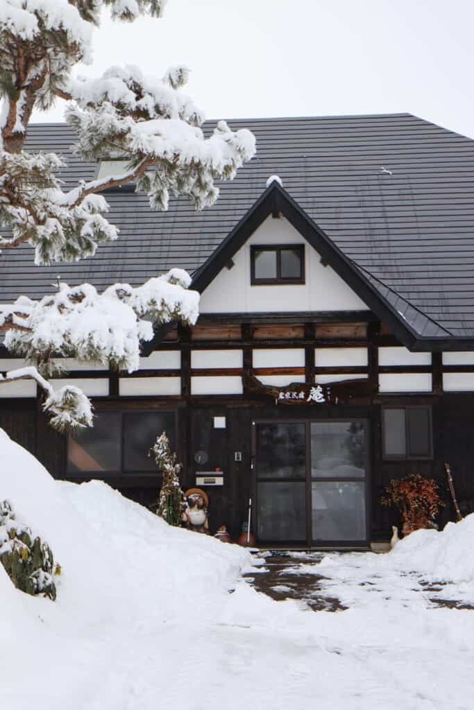 Exterior of the farm stay with snow covered trees  in Semboku, Akita, Japan
