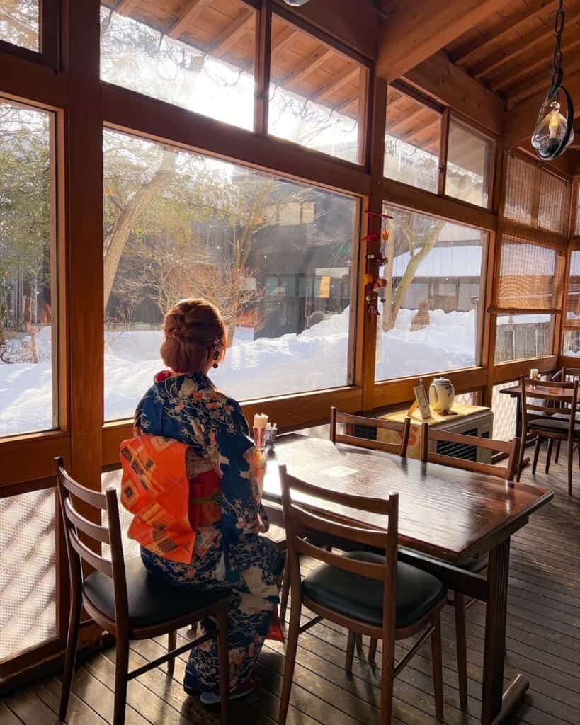 girl wearing a kimono inside cafe looking out of the window in  Japan
