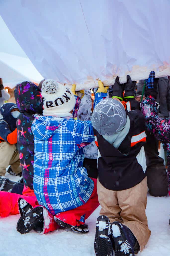 Kids kneeling down to raise the paper balloon in Semboku, Akita, Japan