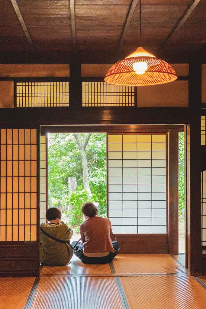 two people sitting at Yanohara Family Residence, a traditional Japanese house, at Sankeien garden