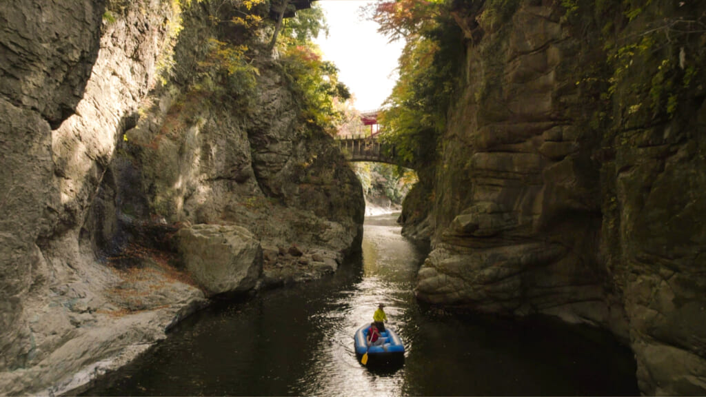 Person on a boat on a river between mountains