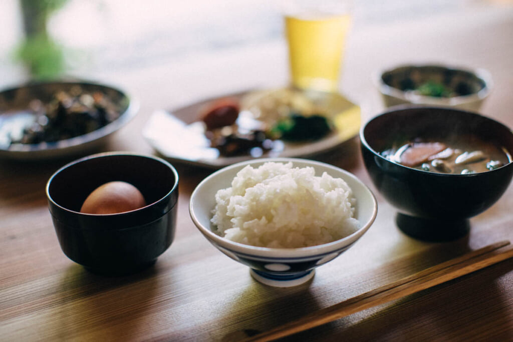Japanese breakfast of rice, raw egg, miso  soup, on a wood table
