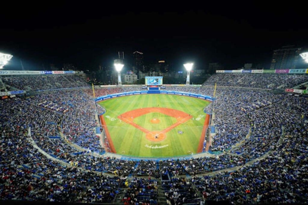 An overhead view of Yokohama Stadium at night, filed with fans watching a baseball game.