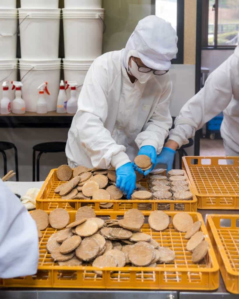 person dressed in white handling crackers in factory