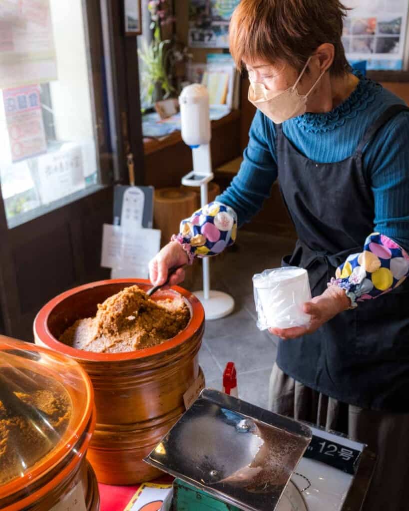 woman scooping miso from ceramic jar