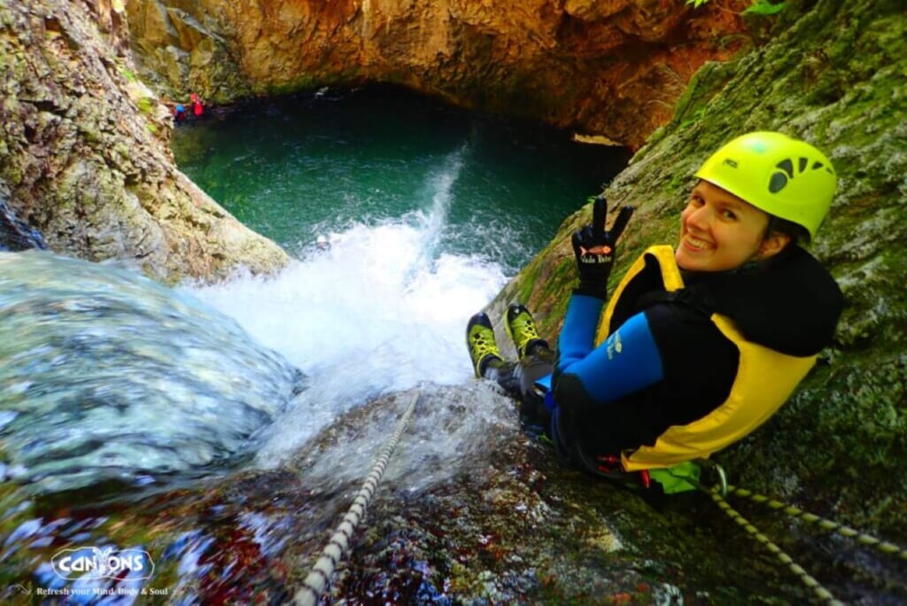 Woman canyoning on the Fox Canyon Tour, about to slide down a waterfall