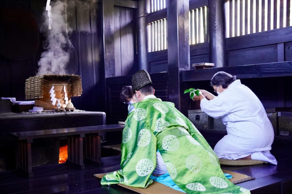 Shinto priest with 2 azome praying during Narukama ritual at Okamaden at Kibitsu Shrine