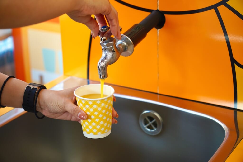 filling a cup of fresh mikan juice from a faucet