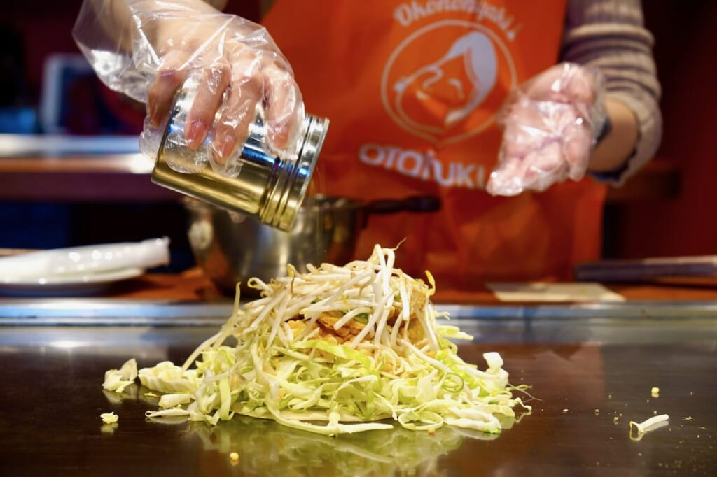 seasoning pile of ingredients on grill for okonomiyaki workshop