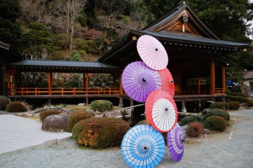 colorful open parasols in front of a wooden noh stage