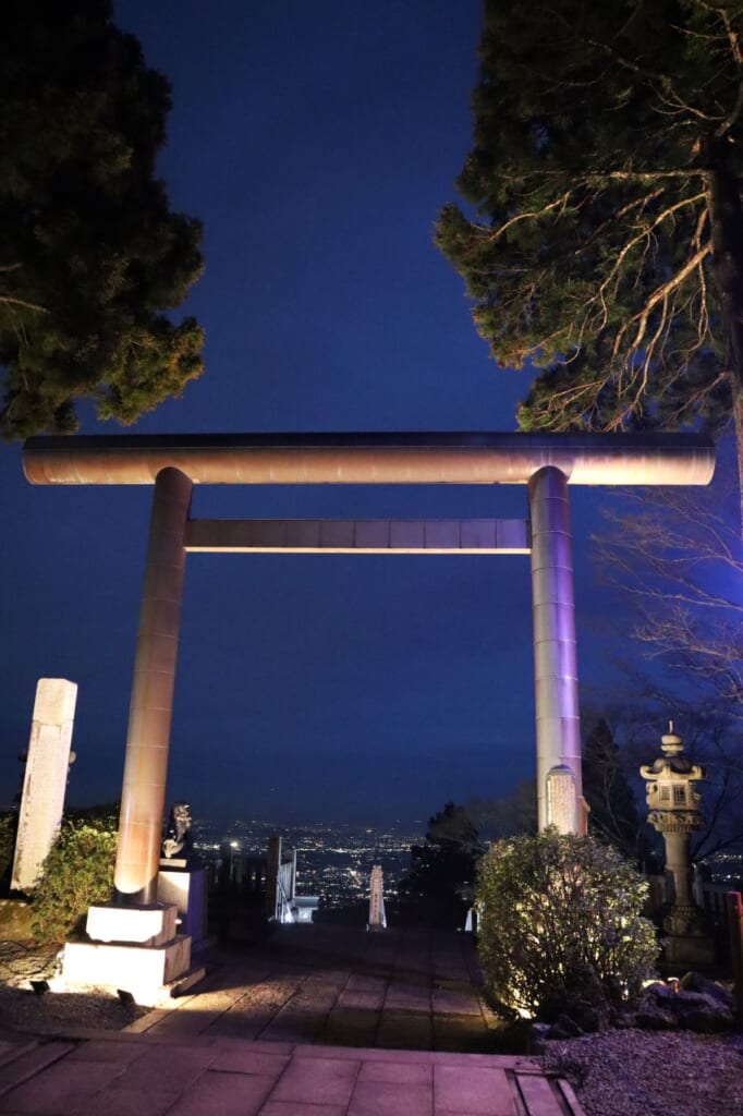 large torii overlooking night cityscape below