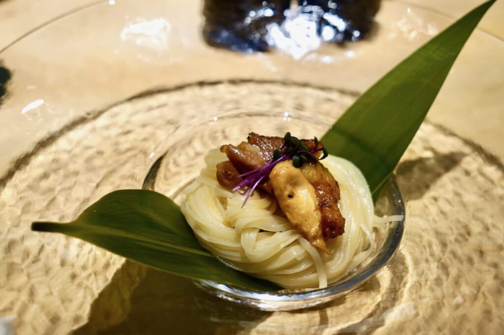 Inaniwa Udon topped with Hinai-jidori chicken served in a glass bowl