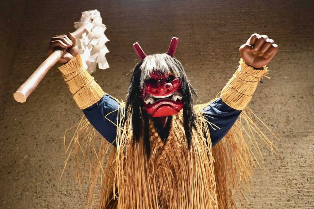 red masked namahage figure in straw costume 