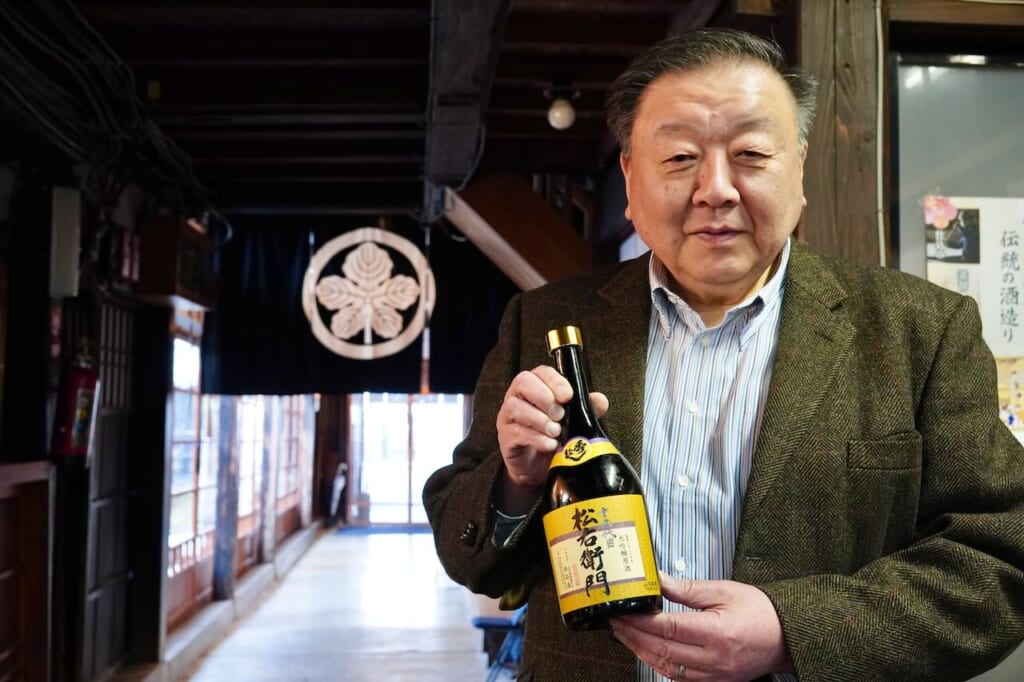 Naoki Suzuki, president of Suzuki Sake Brewery, holds a bottle of sake