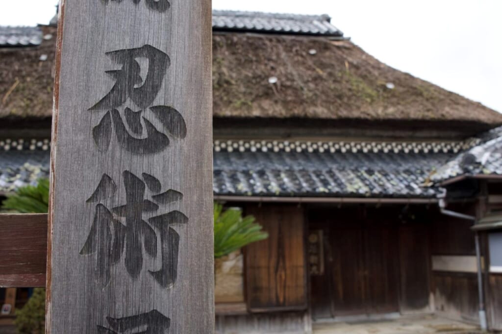 Sign with kanji characters in front of the thatched roof of the Koka Ninja House