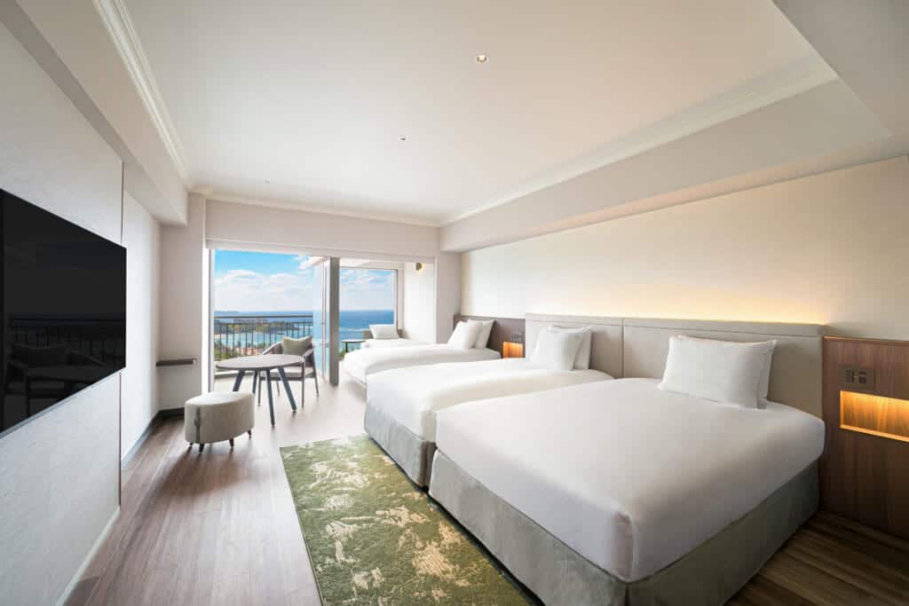 spacious hotel room with two beds and an ocean view in Okinawa, Japan