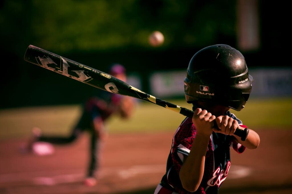 back of kid with helmet swinging a baseball bat in Japan