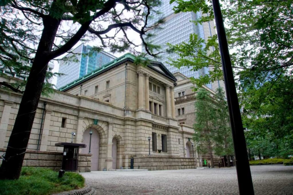 The bank of Japan with white stone walls and green roof tiles in front of sky-scrapers