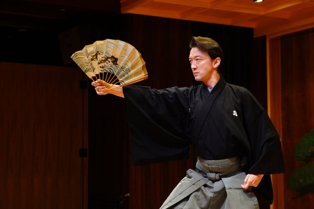 A man holding a fan with a Japanese wave design