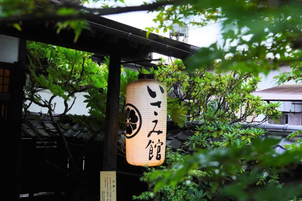 A white lantern with Japanese text amid greenery