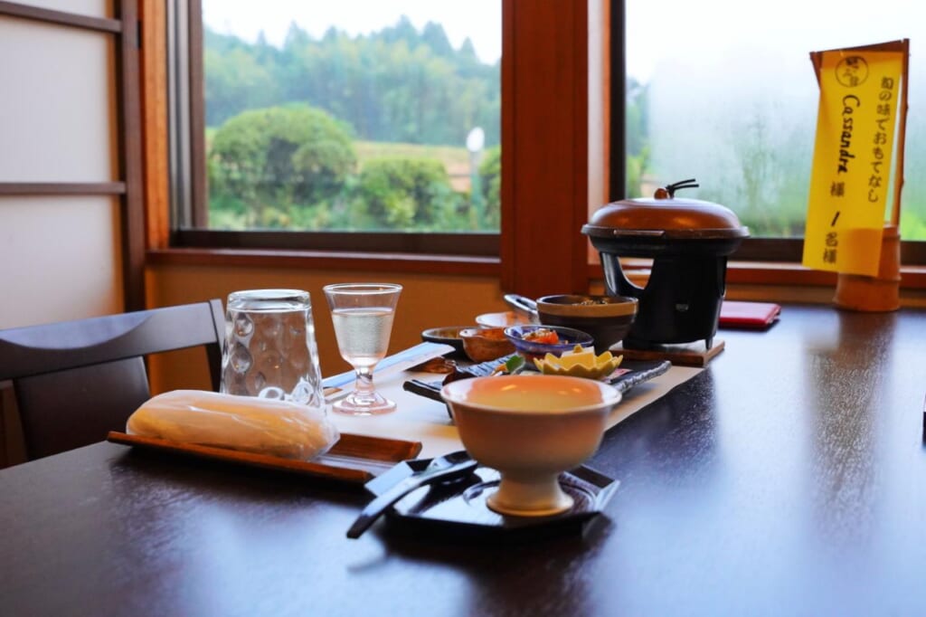 A traditional Japanese dinner on a dark wood table with a window in the back