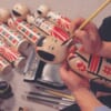 person painting a japanese kokeshi doll