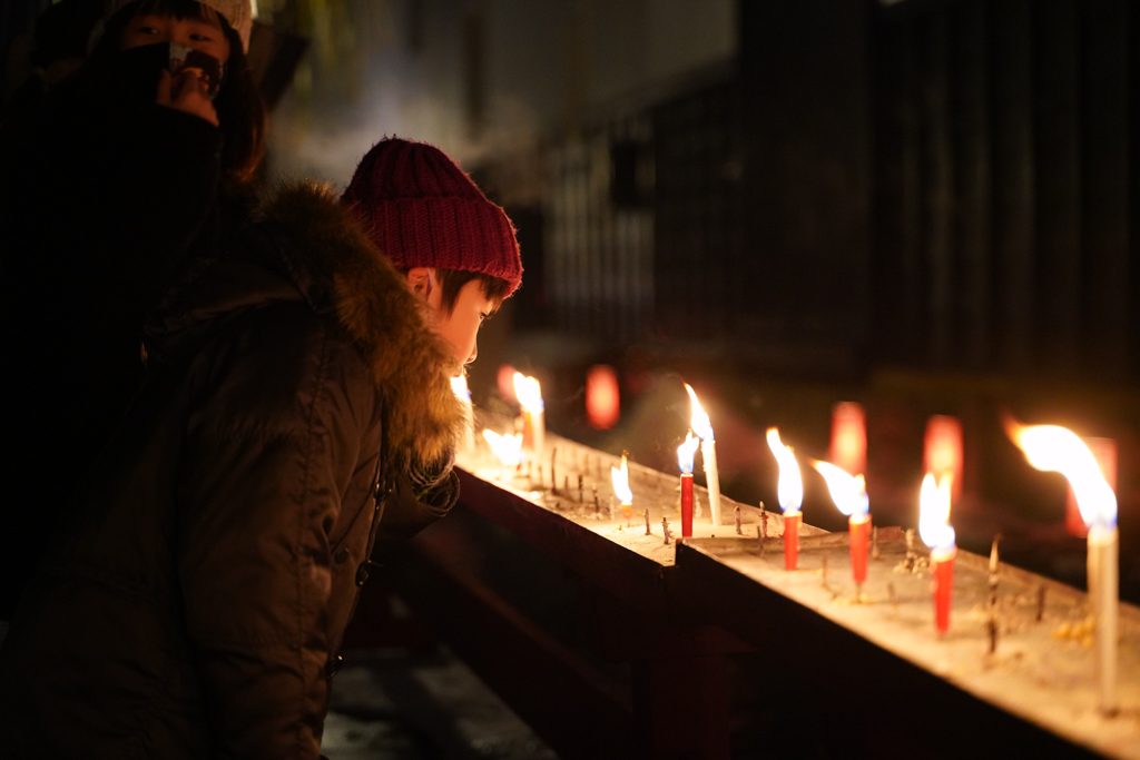 A boy staring a candle at Santera Mairi Festival