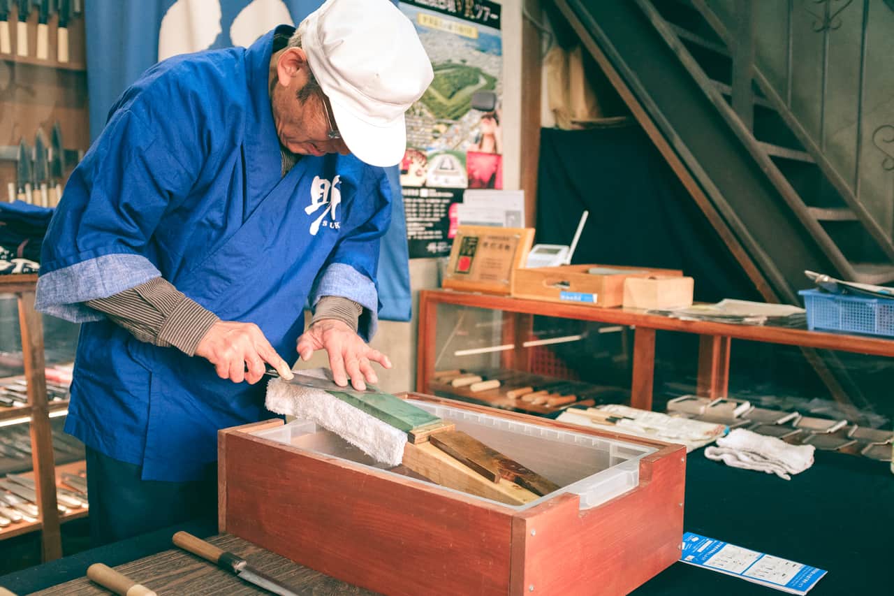 Artisan réaffutant une lame sur une pierre à eau, boutique Wada, Sakai, Osaka, Japon