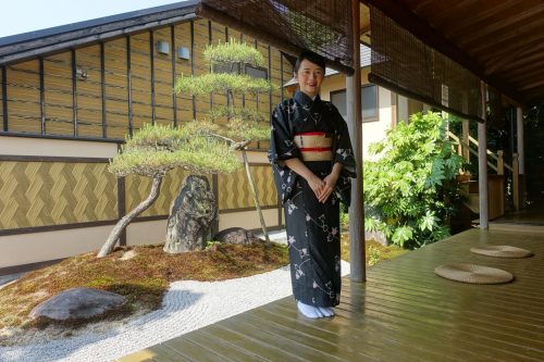 Une employée vêtue d'un kimono, devant le jardin japonais du ryokan Shinsen de Takachiho