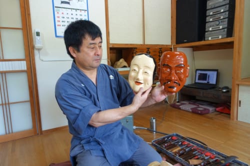 Le maître artisan montre des masques de kagura qu'il vient de réaliser 