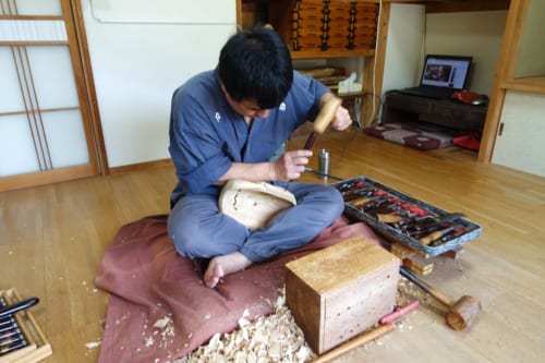 Le maître artisan en pleine sculpture d'un masque de kagura dans son studio