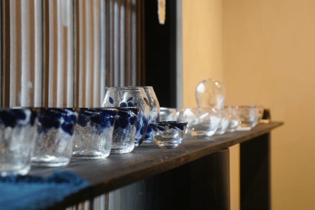 Verres et autres pièces en verre soufflé réalisées à Asuka, exposées dans une maison traditionnelle.
