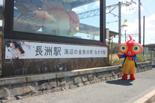 Statue géante représentant un poisson rouge et mascotte de Nagasu, devant la gare