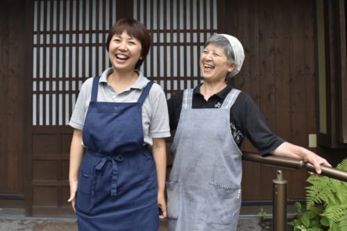 Yuri et sa mère, tout sourire devant leur maison d'hôtes à Ubuyama