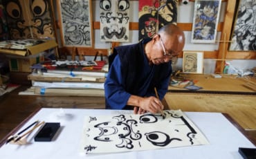 Un artisan peint les contours d'un personnage sur un cerf-volant traditionnel dans son atelier à Yuzawa, préfecture d'Akita