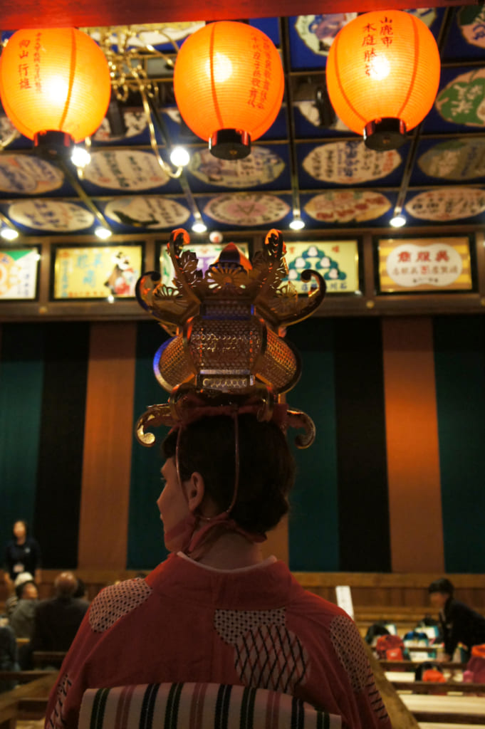 Clémetine de dos, lanterne sur la tête, dans le théâtre Yachiyo-za de Yamaga