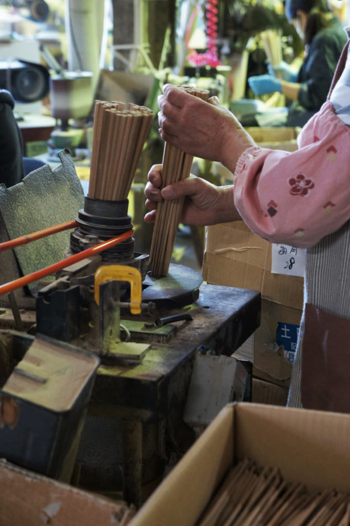 Mains d'une ouvrière qui travaille sur des finitions de baguettes à l'usine de Yamachiku