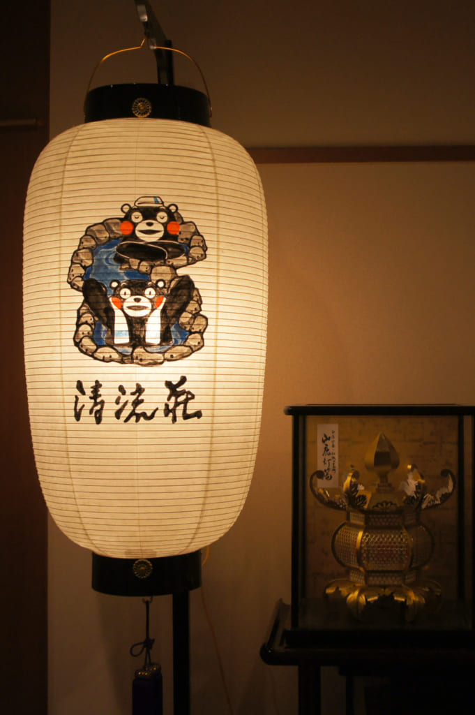 Lanterne de papier sur laquelle est peint Kumamon, à côté d'une lanterne de Yamaga