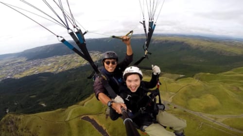 Mika et son instructeur, volant en parapente au-dessus du mont Aso une des activités de plein air à pratiquer à Kumamoto