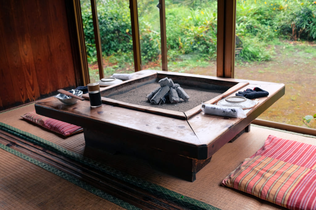 Foyer et charbon au centre d'une table de Takamori Dengaku Hozonkai donnant sur le jardin