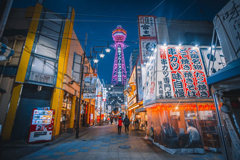 La tour d'Osaka trone dans le quartier de Shinsekai, éclairé de couleurs différentes en fonction des saisons