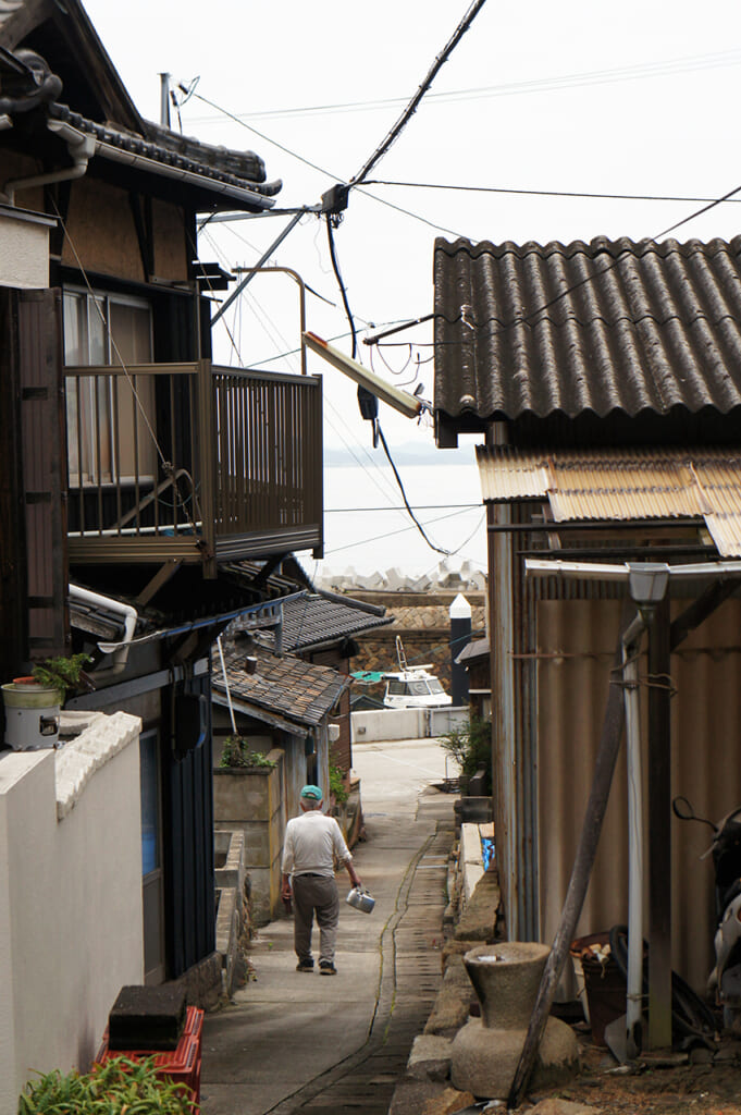 Vieil homme marchant dans les ruelles d'un village portuaire japonais
