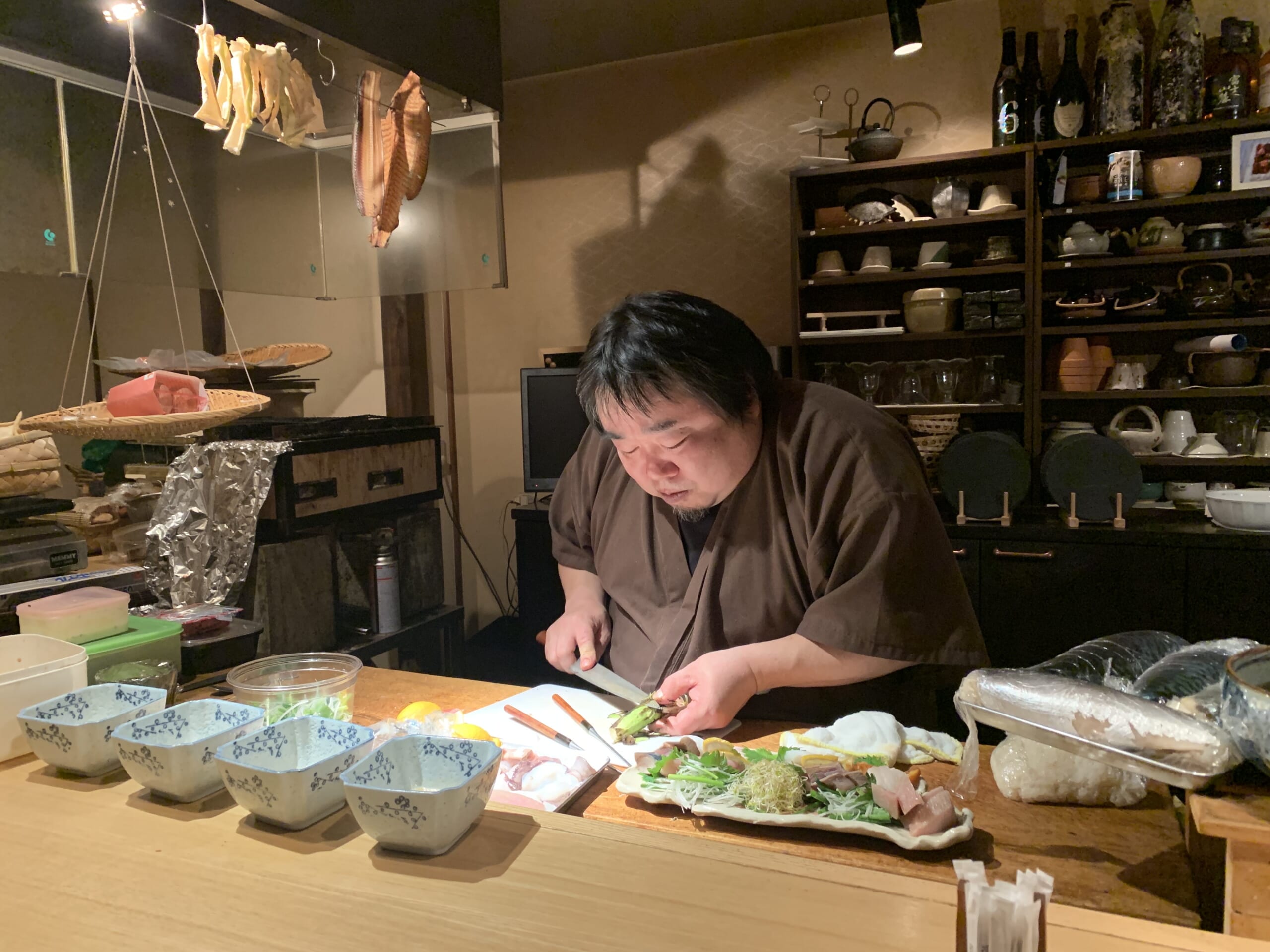 cuisinier japonais entrain de préparer un plat de sashimis