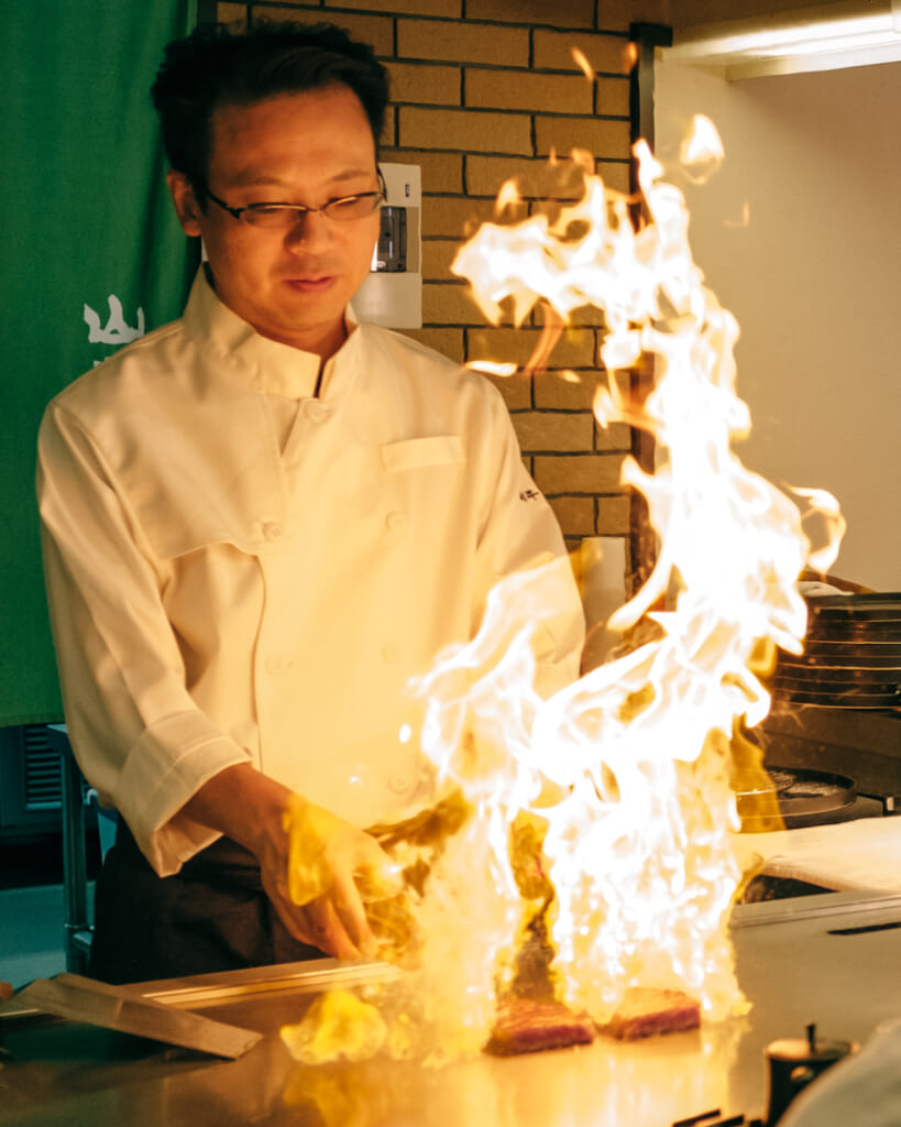 cuisinier faisant flamber de la viande dans un restaurant de teppanyaki auy Japon